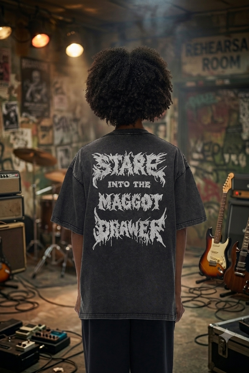 Person wearing a black t-shirt with white text in a rehearsal room filled with musical equipment.