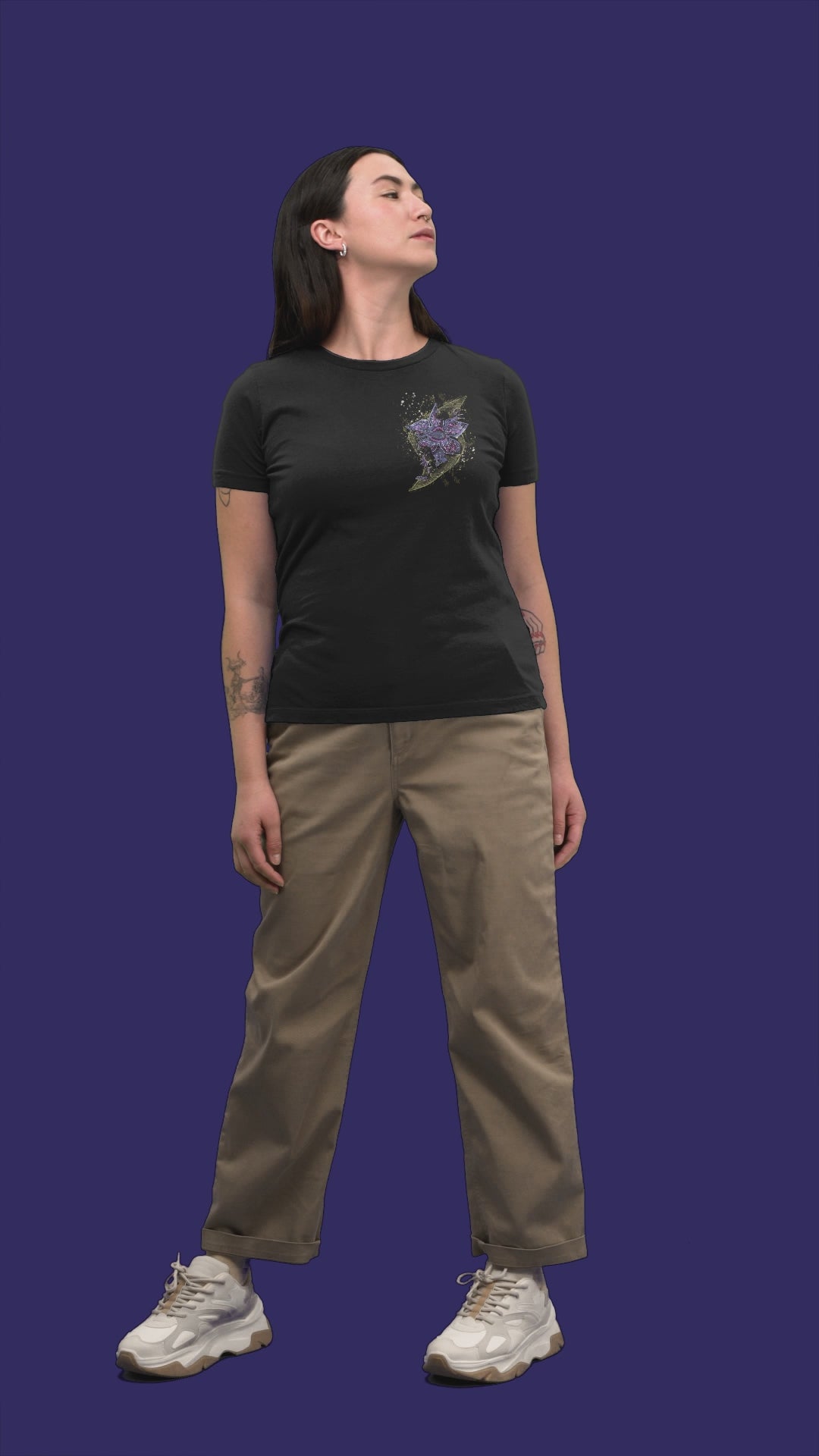 Video showing a  female 
model wearing a black t-shirt, highlighting both the abstract purple and gold  Stranger Things inspired graphic on front , and "We've Been Building It For You" text on the back.